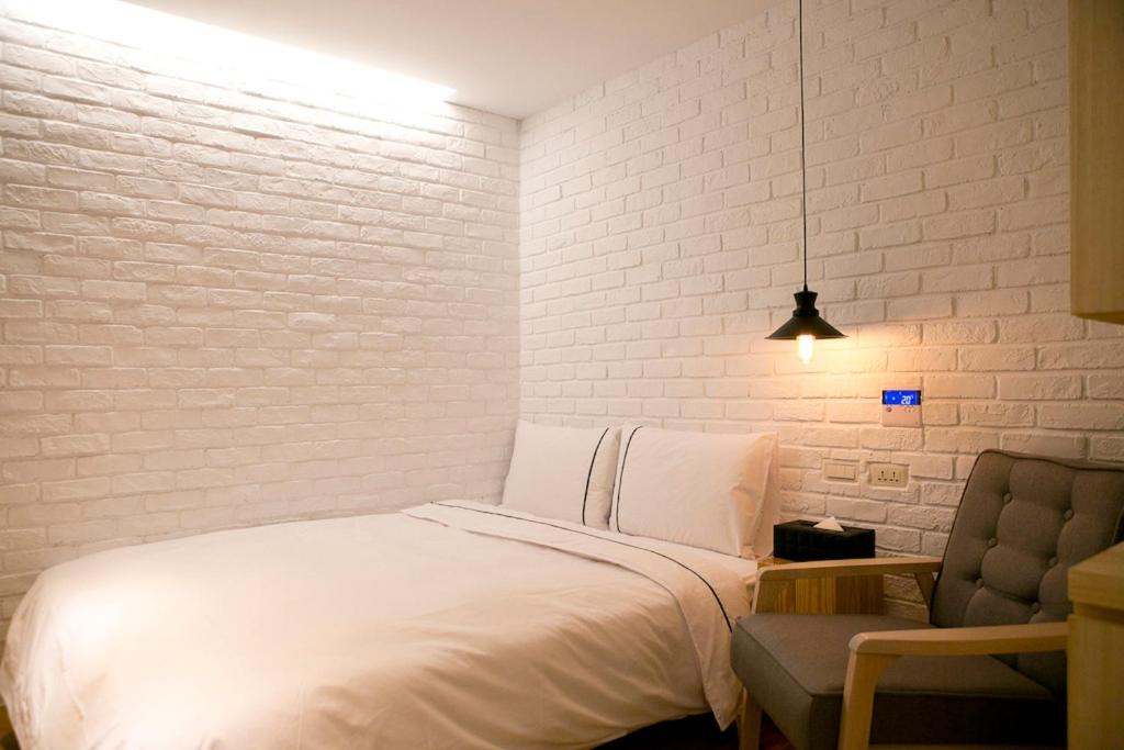 a white bedroom with a bed and a chair at York Hotel in Taipei