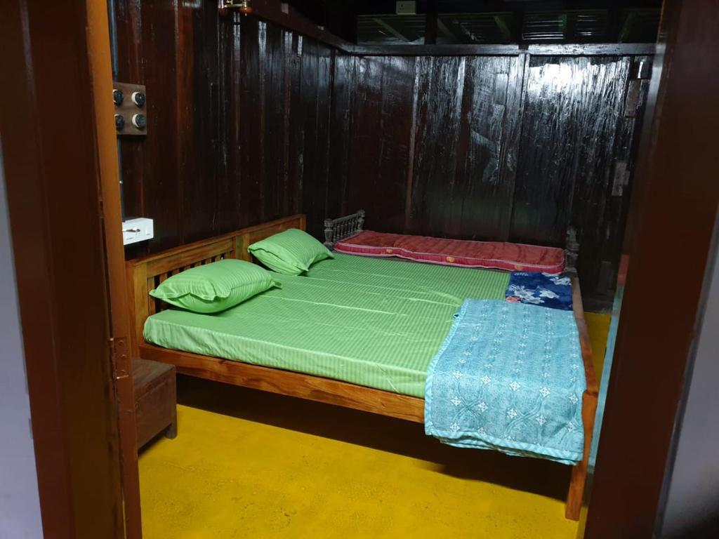 - une chambre dotée d'un lit en bois avec des draps et des oreillers verts dans l'établissement Nutmeg nirvana, à Erāttupetta