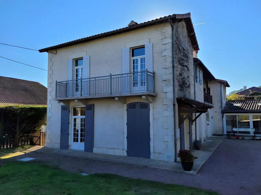 Una casa blanca con un balcón al costado. en Au Grand Mur, en Neuvic
