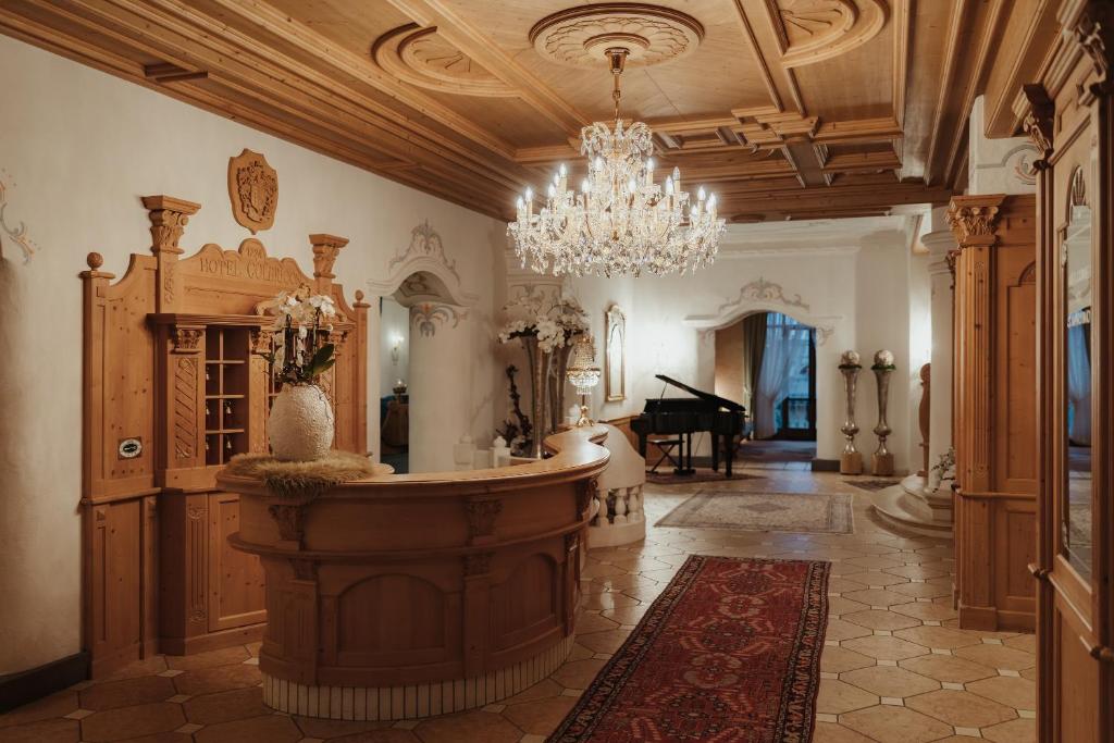 a large room with a chandelier and a room with a table at Hotel Colbricon in San Martino di Castrozza