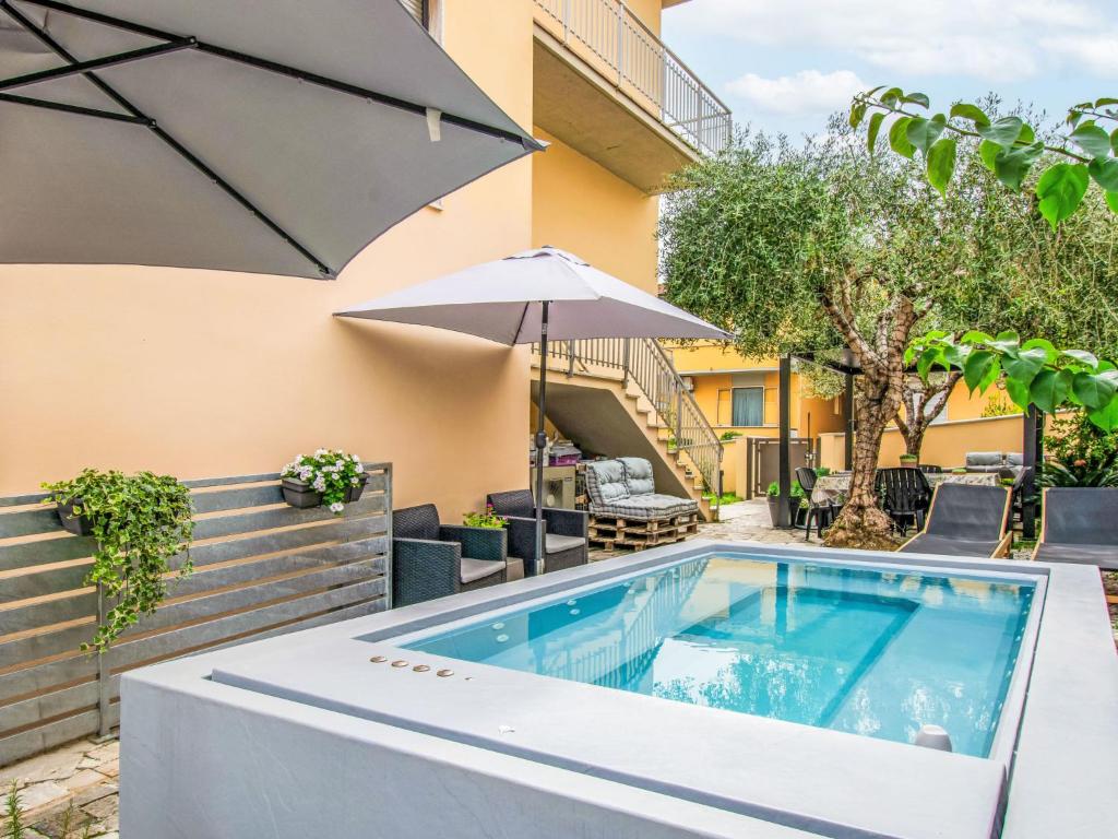 een buitenzwembad met een parasol en een parasol bij Apartment Michelle by Interhome in San Romano
