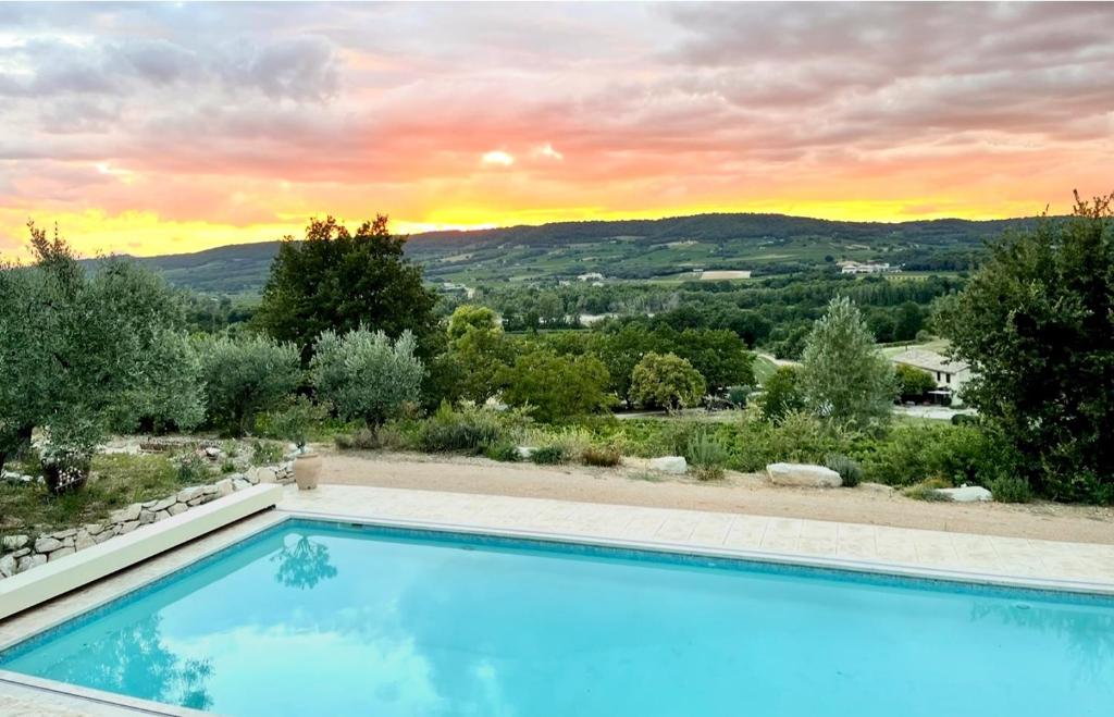 a swimming pool with a sunset in the background at Le Baiser du Soleil - Piscine Privée in Mirabel-aux-Baronnies