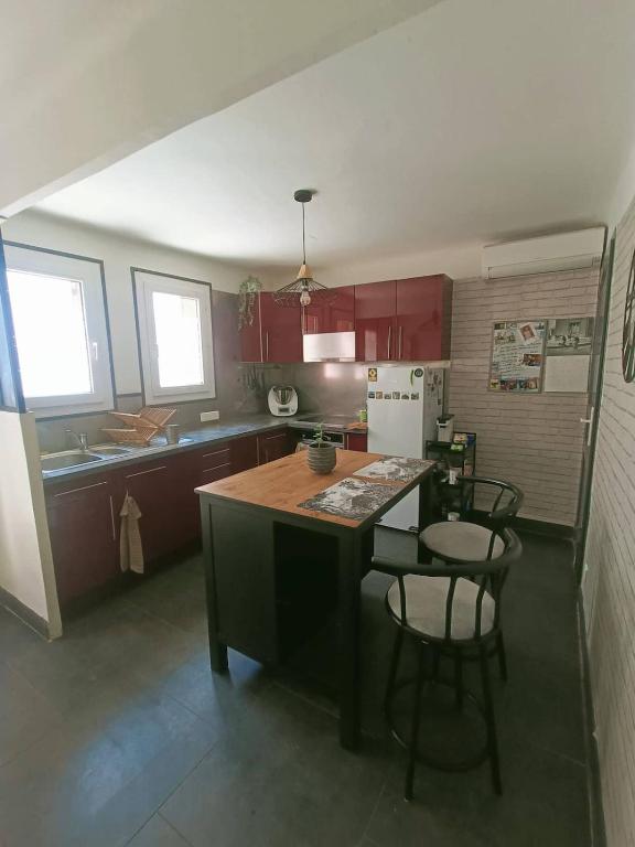 una cucina con armadi rossi e un'isola cucina con sedie di La parenthèse ardéchoise a Le Pouzin