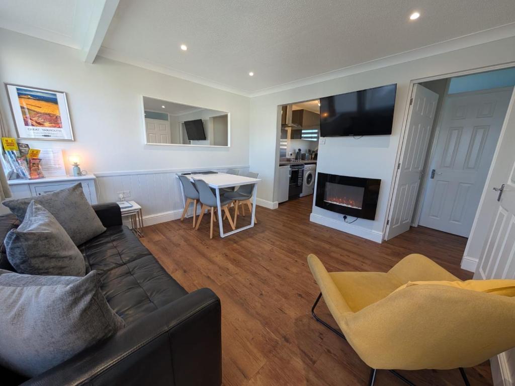 a living room with a couch and a fire place at Beachcomber, Two bed Chalet on Sunbeach Holiday Park - Sleeps 4, pet friendly, FREE pool and entertainment passes included - plus WiFi - only 300m from the beach! in Scratby