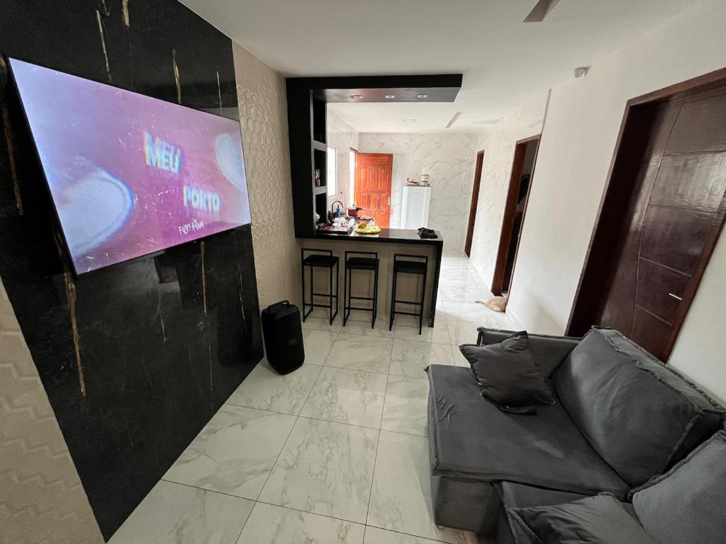a living room with a couch and a large screen at Casa para repouso in Mamanguape