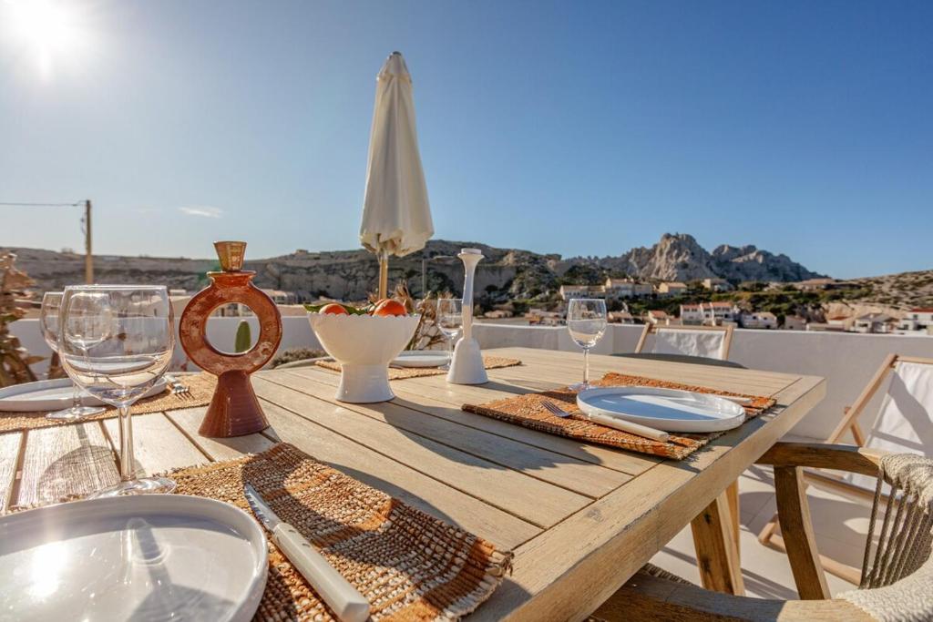 een houten tafel met wijnglazen en uitzicht op de stad bij Villa aux Goudes in Les Goudes