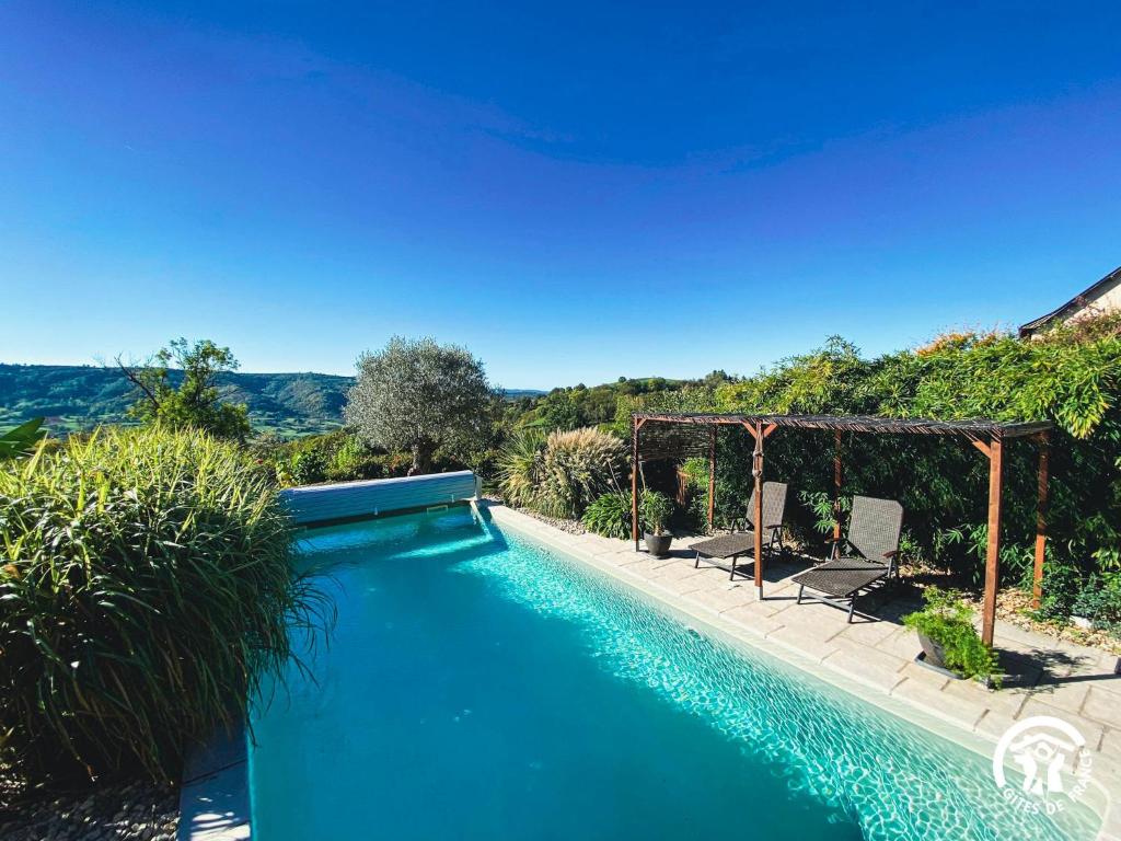 a swimming pool with two chairs and a gazebo at La Prunille in Pruines