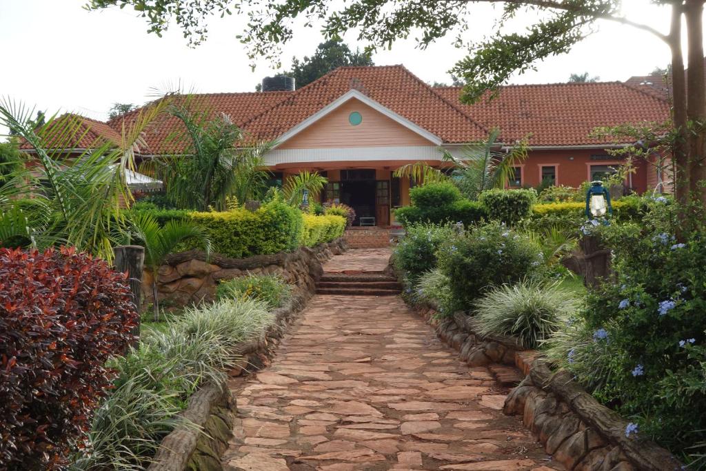 a house with a stone walkway in front of a yard at Impala Suites in Jinja