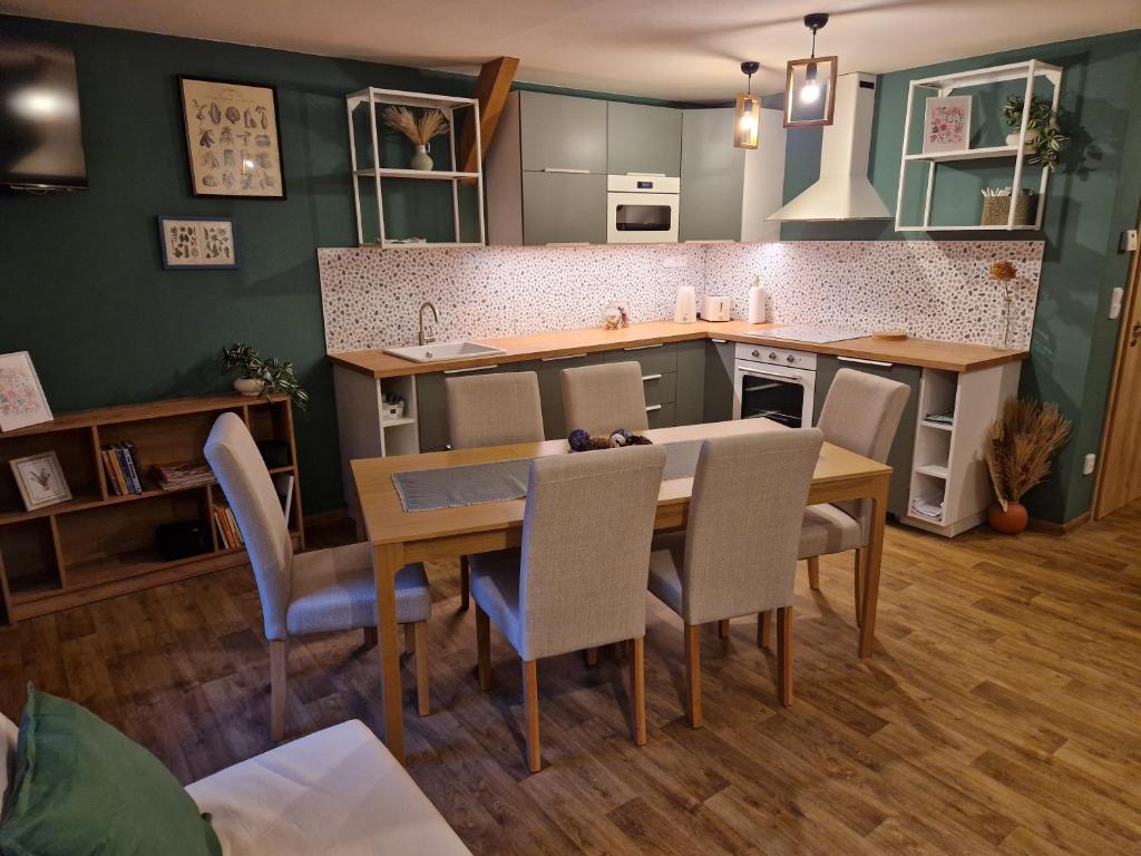 Una cocina y un comedor con mesa y sillas. en Apartmány KOUTY 23, en Kouty
