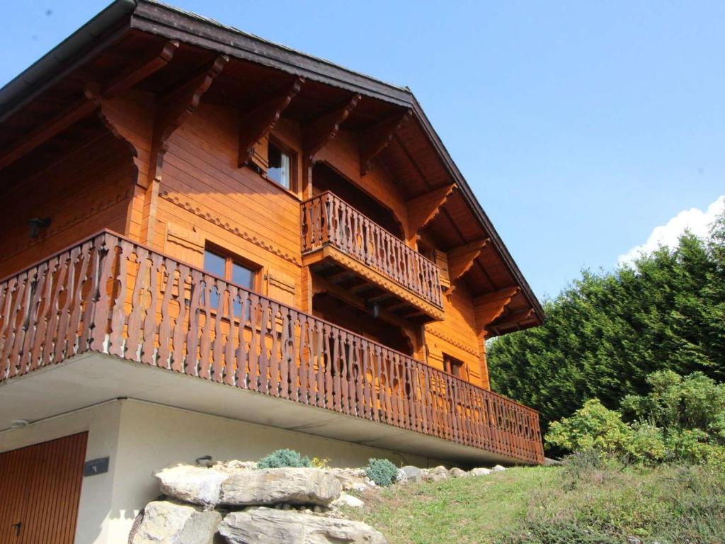 ein großes Holzhaus mit Balkon auf einem Hügel in der Unterkunft Chalet typique 10 pers, Arâches-la-Frasse - FR-1-572-27 in Arâches-la-Frasse