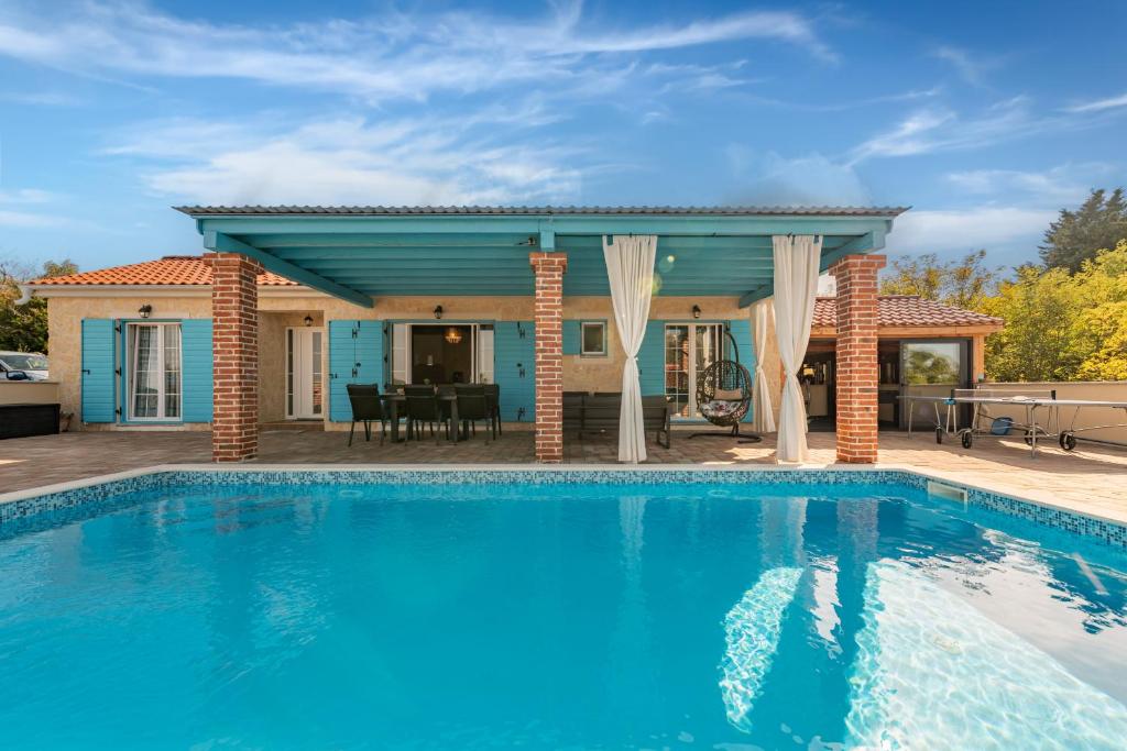a swimming pool in front of a house at Stone villa Jurenda with pool in Debeljak
