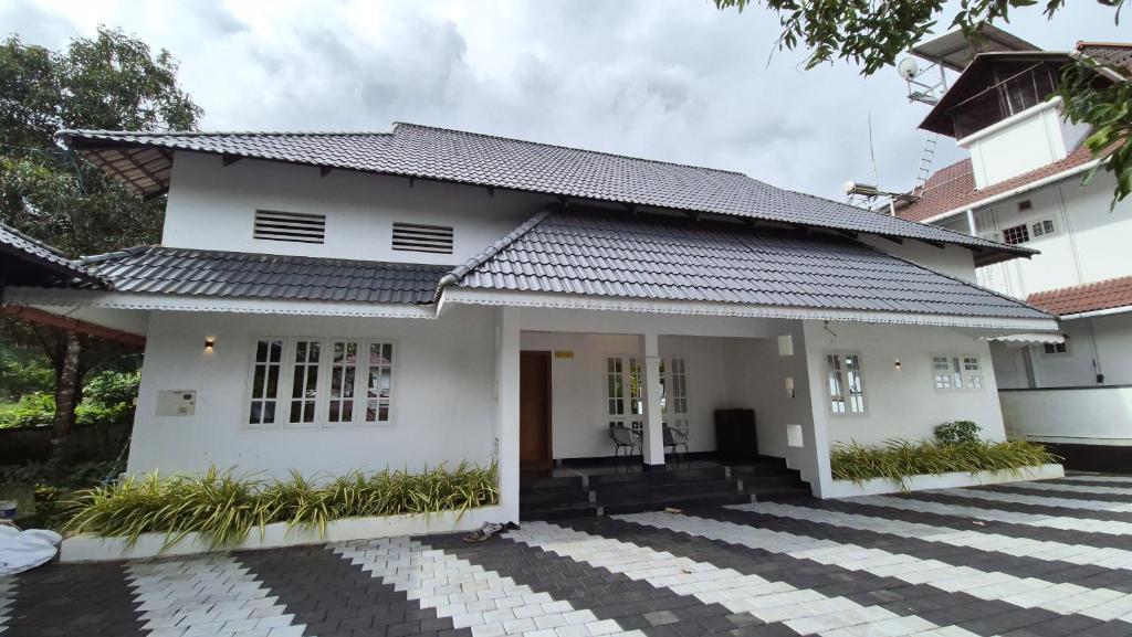 a white house with a black roof at Nest&Nook in Ettumānūr