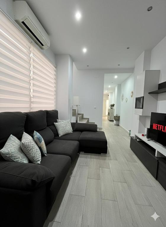 a living room with a black couch and a television at Casa moderna en Manises con 2 terrazas in Manises
