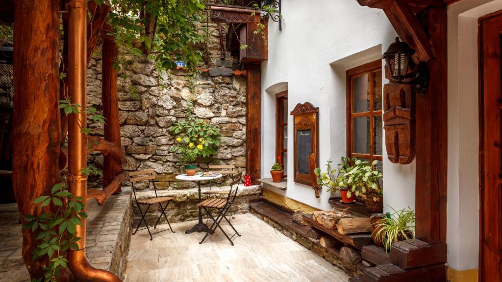 a patio with a table and chairs and a stone wall at Penzion Barborka in Poprad