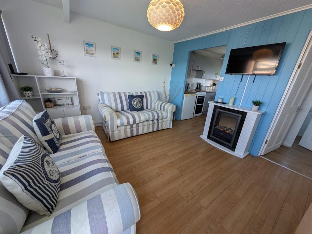 een woonkamer met een bank en een open haard bij 46 Hectors, Sunbeach, Scratby - Two bed chalet, sleeps 4, pet friendly, free Wi-Fi, free entry to onsite clubhouse and bed linen and towels included in Great Yarmouth