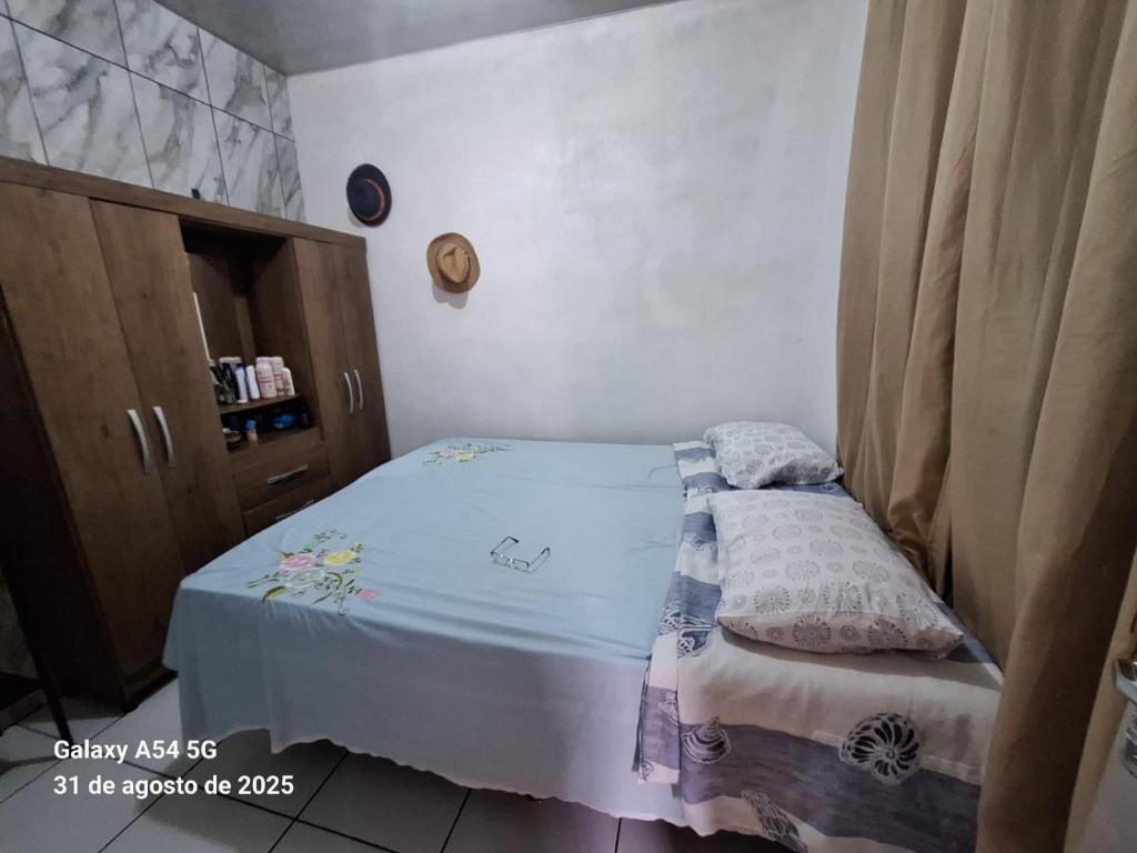 a small bedroom with a bed and a wooden cabinet at Casa de Praia in Mosqueiro