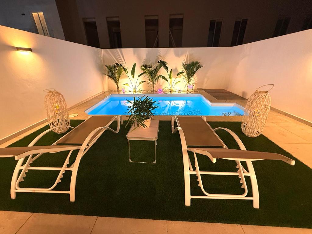 Una piscina con una mesa y sillas al lado de una piscina. en Alma Nomada Luxury Village, en Corralejo