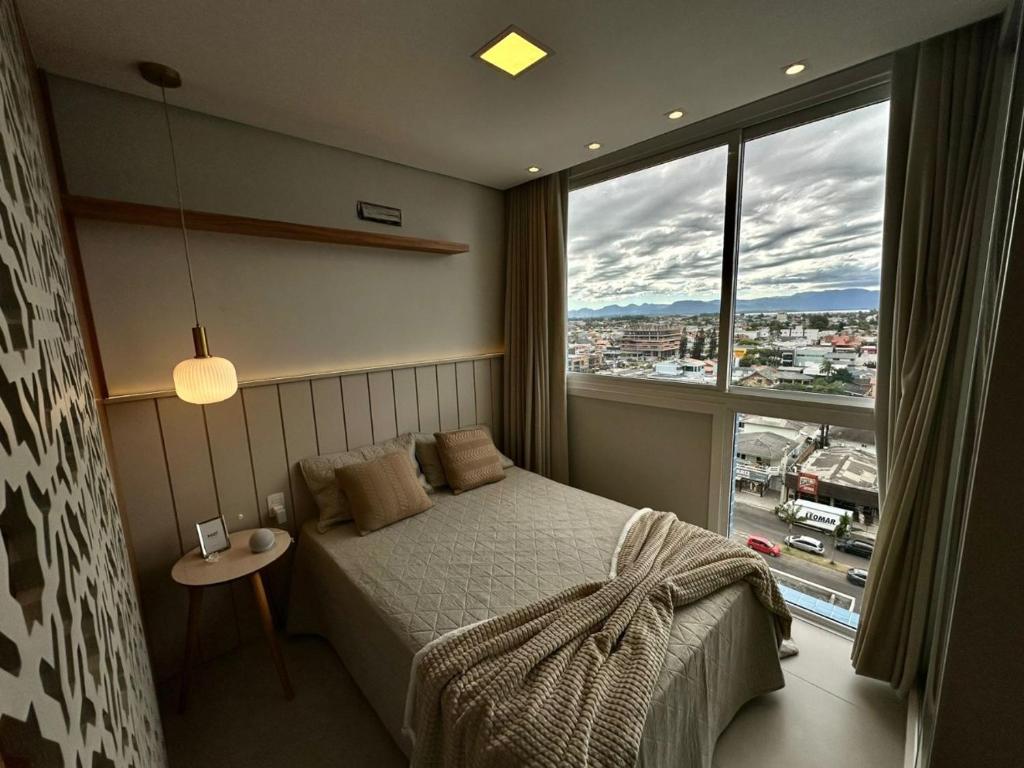 a bedroom with a bed and a large window at Plaza Mayor Loft in Capão da Canoa