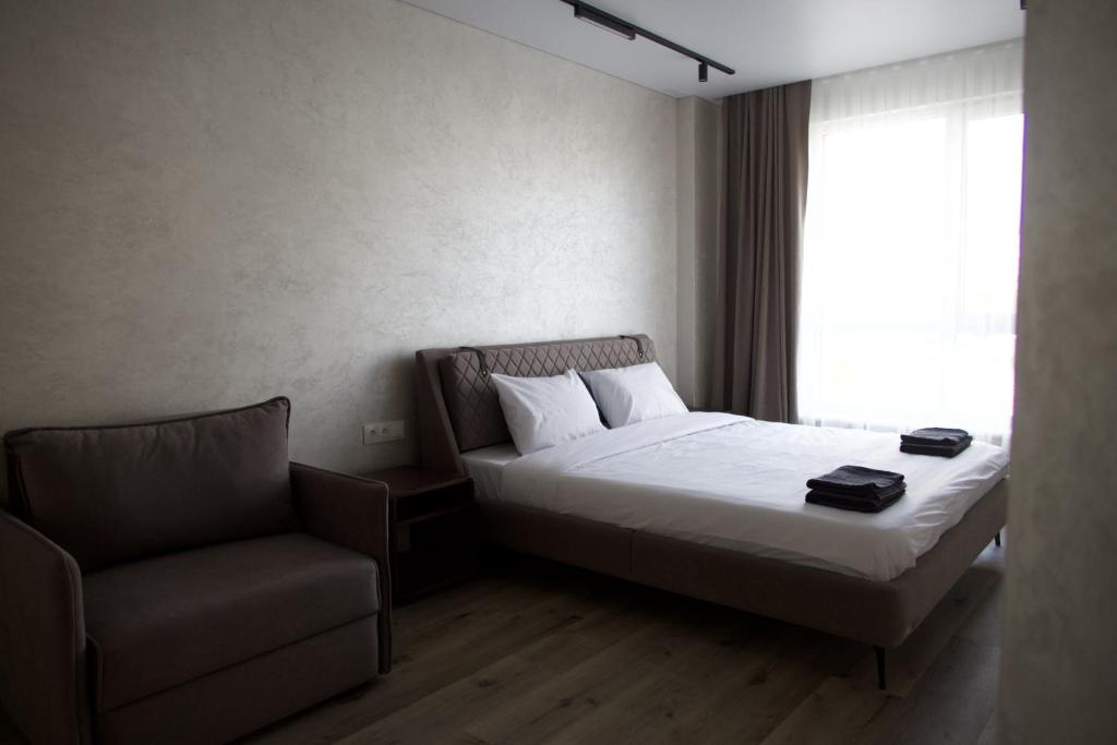 a bedroom with a bed and a chair and a window at Pysanka apartments in Kolomyya