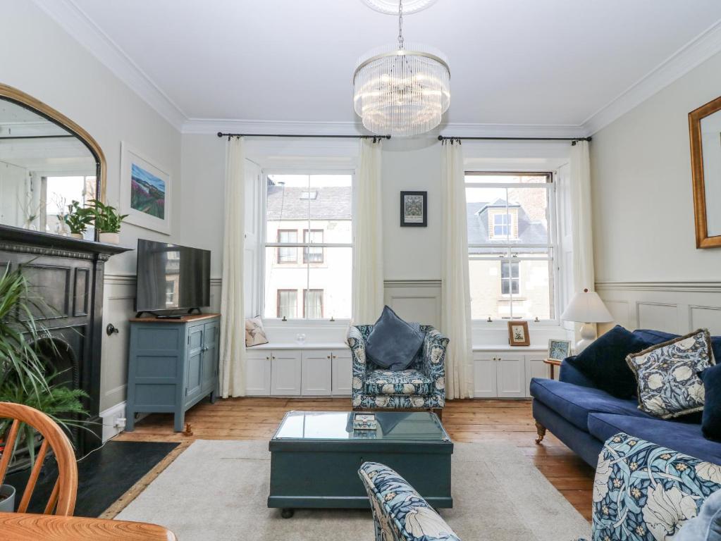 a living room with a blue couch and a tv at 11A High Street in Jedburgh