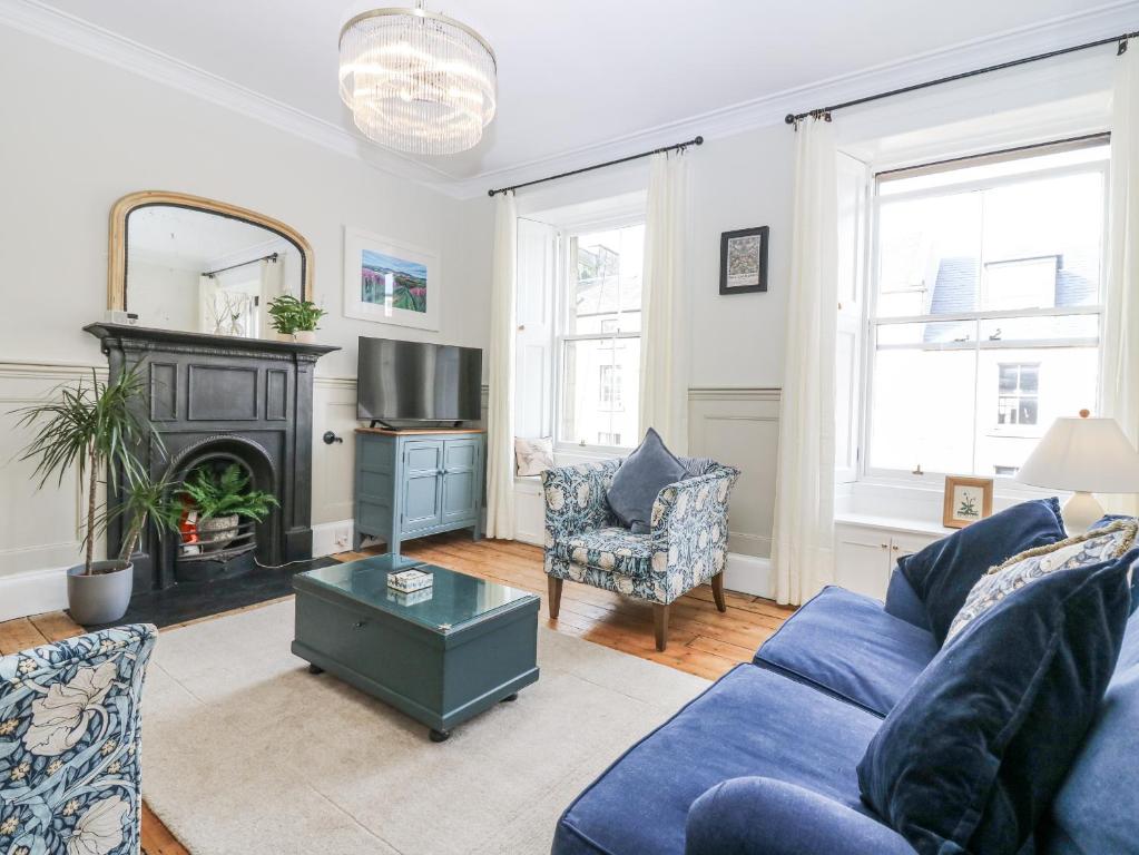 a living room with a blue couch and a fireplace at 11A High Street in Jedburgh
