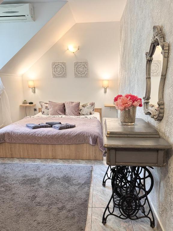 a bedroom with a bed and a table with flowers at Szent Kristóf Panzió in Eger