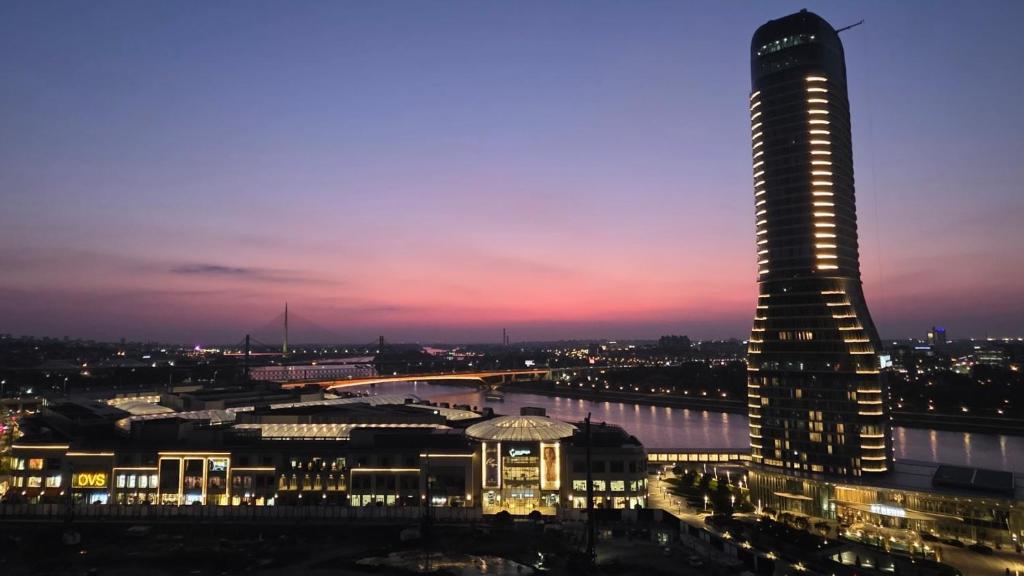 a tall building at night with a city at BW Aqua LUX, river view, parking free in Belgrade