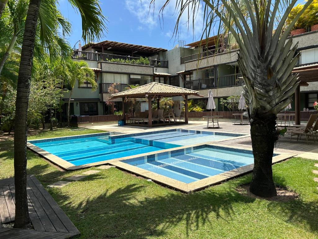a swimming pool with a gazebo next to a building at Praia do Forte Kauai Bahia in Praia do Forte