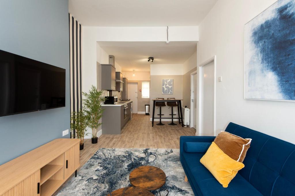 ミドルズブラにあるRio Apartmentsの青いソファとキッチンのあるリビングルーム
