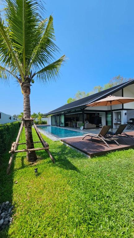 a palm tree next to a building with a pool at 913 Luxury Pool Villa Khaolak in Khao Lak