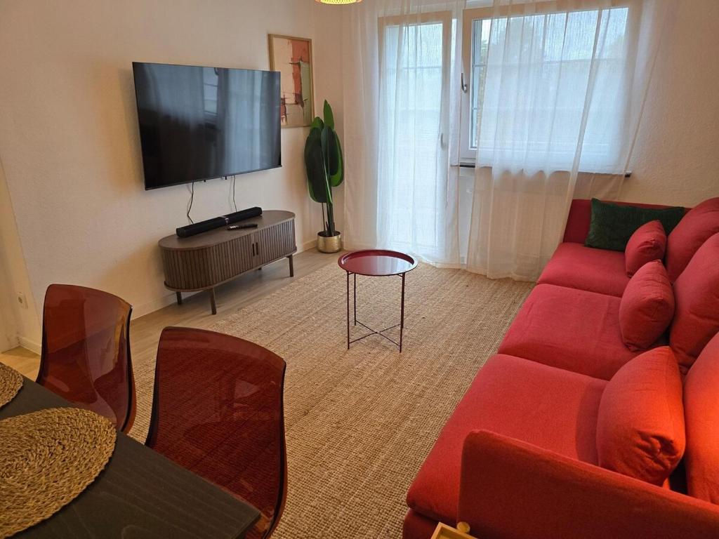 ein Wohnzimmer mit einem roten Sofa und einem Flachbildfernseher in der Unterkunft Modern Köln Flat 20mins Messe 25mins Neumarkt in Köln