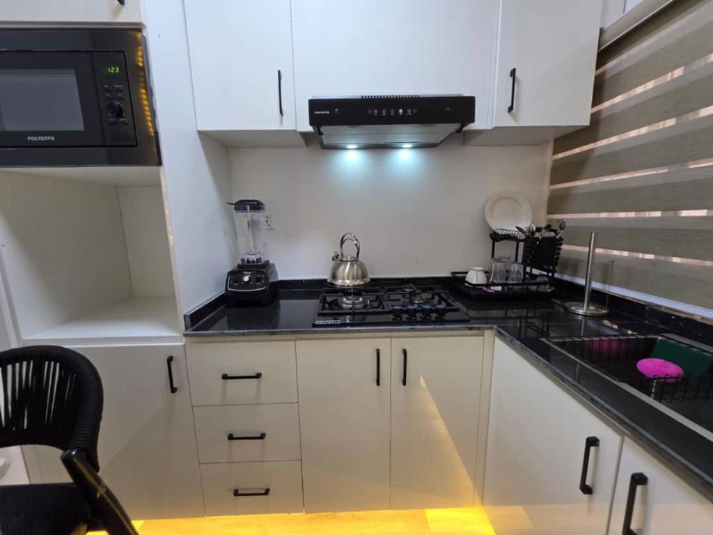 Una cocina con gabinetes blancos y una encimera negra. en Mira Haven Apartments, en Abuja