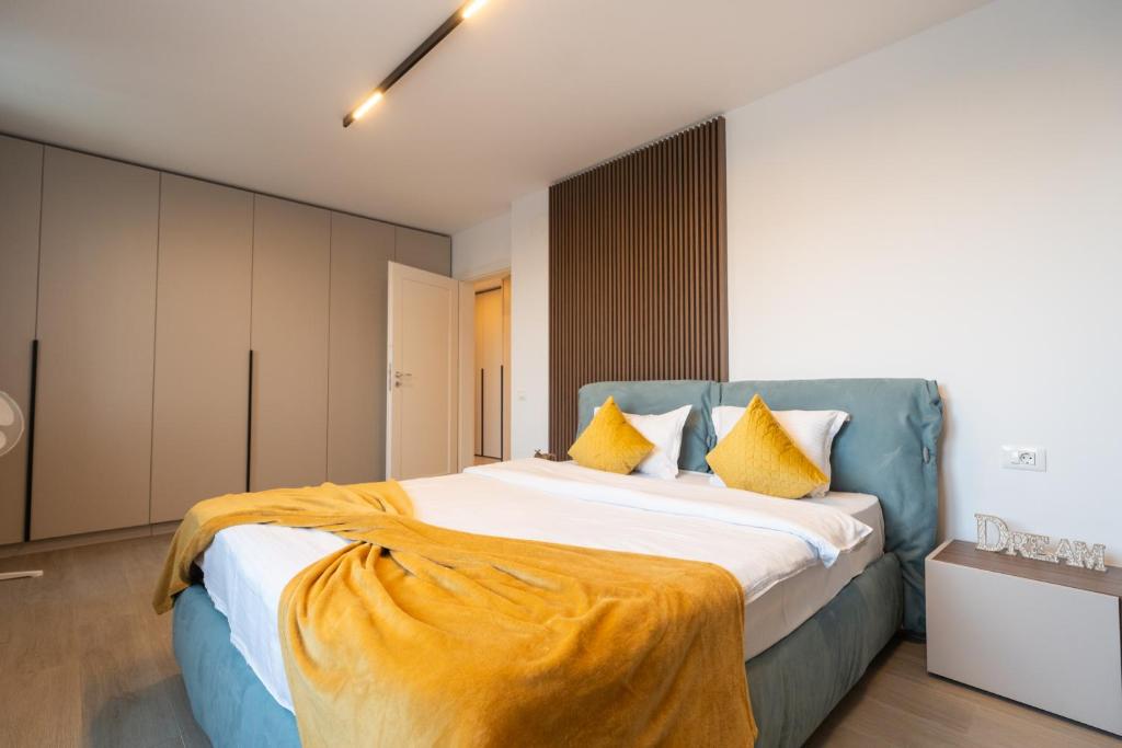 a bedroom with a large bed with yellow pillows at CH Apartments Urban Plaza in Braşov