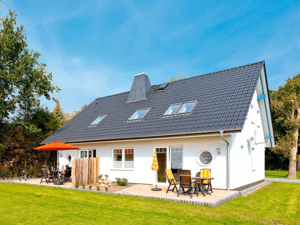 a white house with a patio with chairs and tables at Ferienhaus LampRieger Fewo 1 OG in Wieck