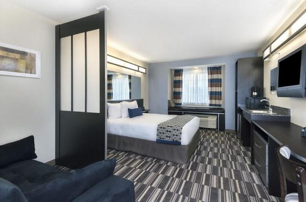 a hotel room with a bed and a couch at Microtel Inn and Suites Baton Rouge Airport in Baton Rouge