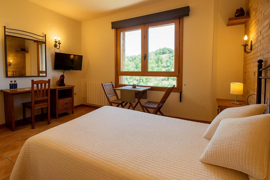 a bedroom with a bed and a table and a desk at Hostal Todolella in Todolella