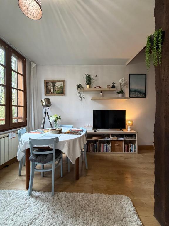 Una sala de estar con una mesa y un televisor. en Dove Nest, en Figeac
