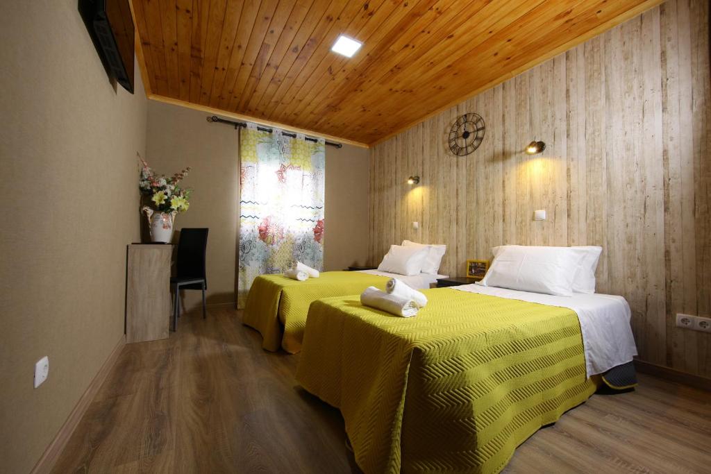 a hotel room with two beds with yellow sheets at Happy House in Faro