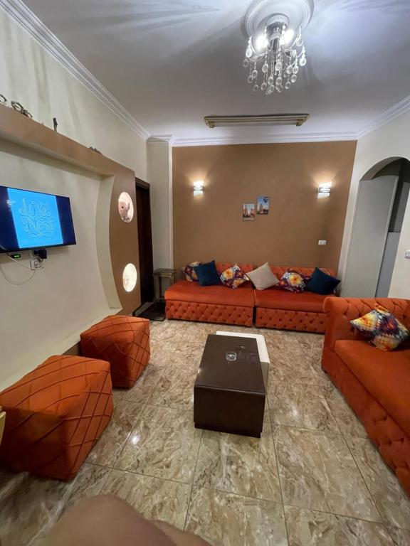 a living room with orange couches and a tv at Luxe Nest Luxor Serviced Apartments 101 in Luxor