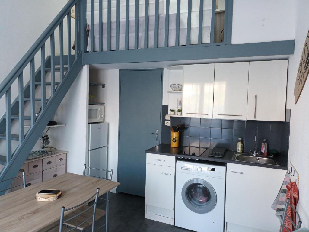 a kitchen with a washing machine and a staircase at Villa Pinede du Golf PORT LEUCATE in Port Leucate