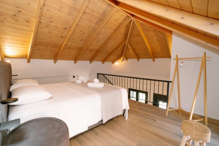 een slaapkamer met een groot wit bed en houten plafonds bij RoDous Luxury Apartments Preveza in Preveza