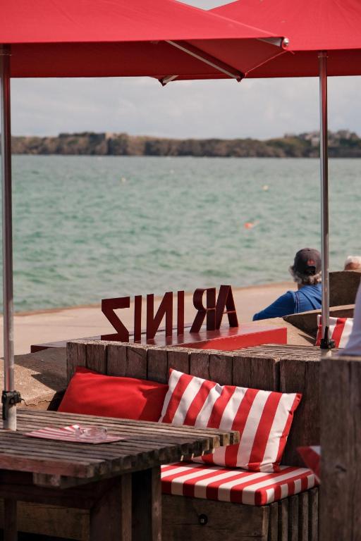 a table and chairs with a red umbrella and water at Hôtel Restaurant Ar Iniz in Saint Malo