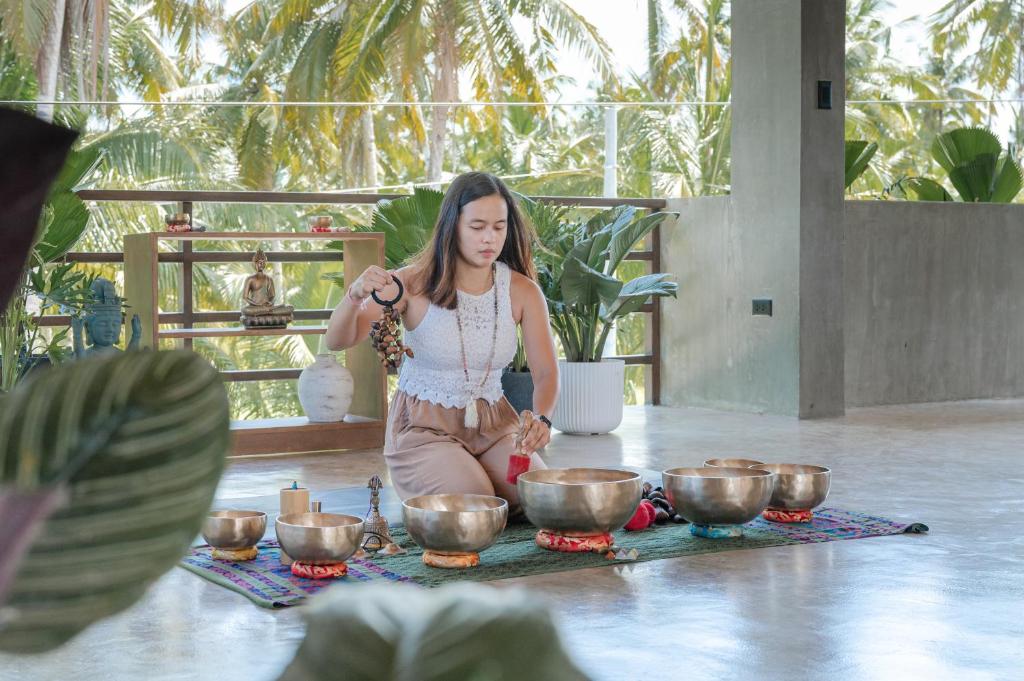 a woman sitting on the floor in front of bowls at Anantha Wellness Sanctuary in General Luna
