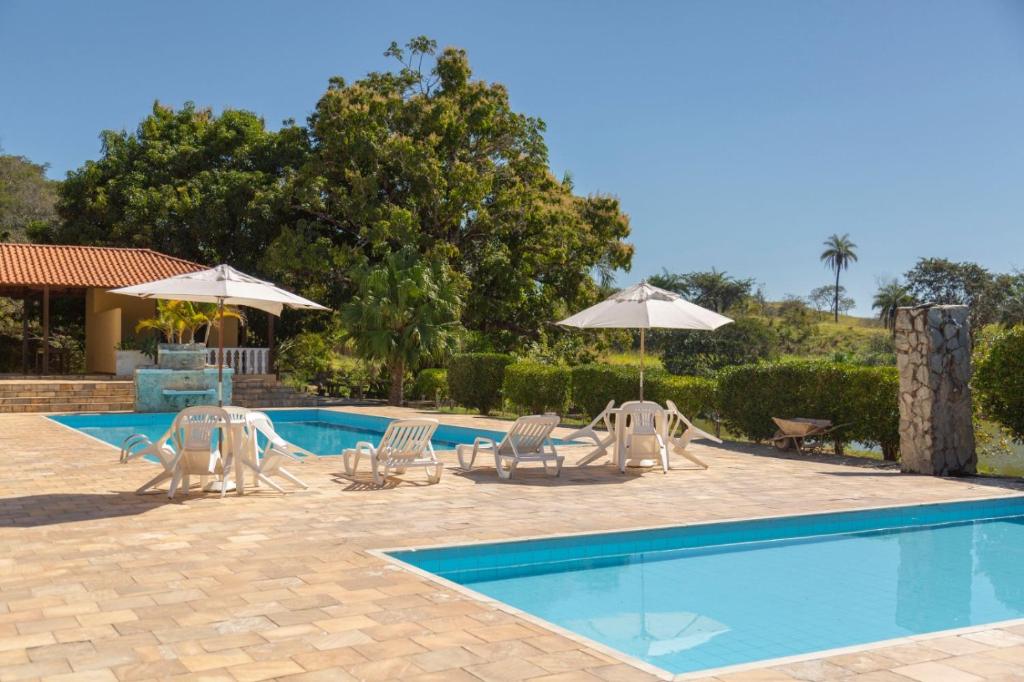 a swimming pool with lounge chairs and umbrellas next to at Hotel Fazenda Moinho in Esmeraldas