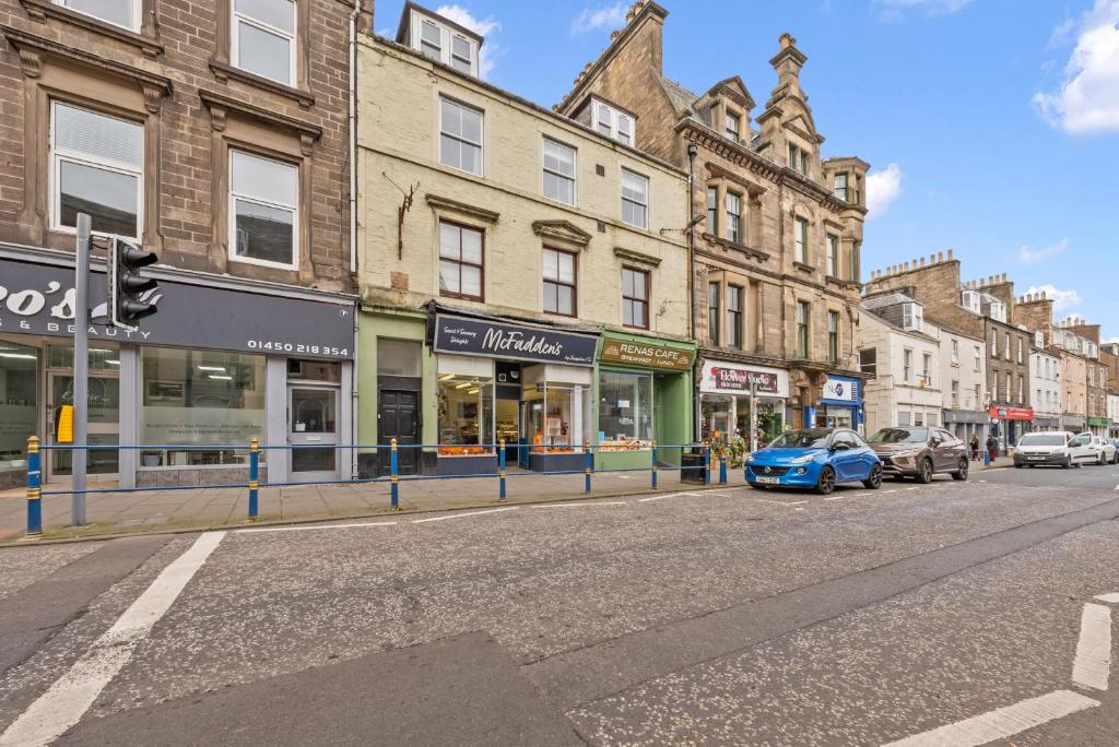 a city street with cars parked in front of buildings at Comfortable 4 Bedroom Apartment - Hawick in Hawick