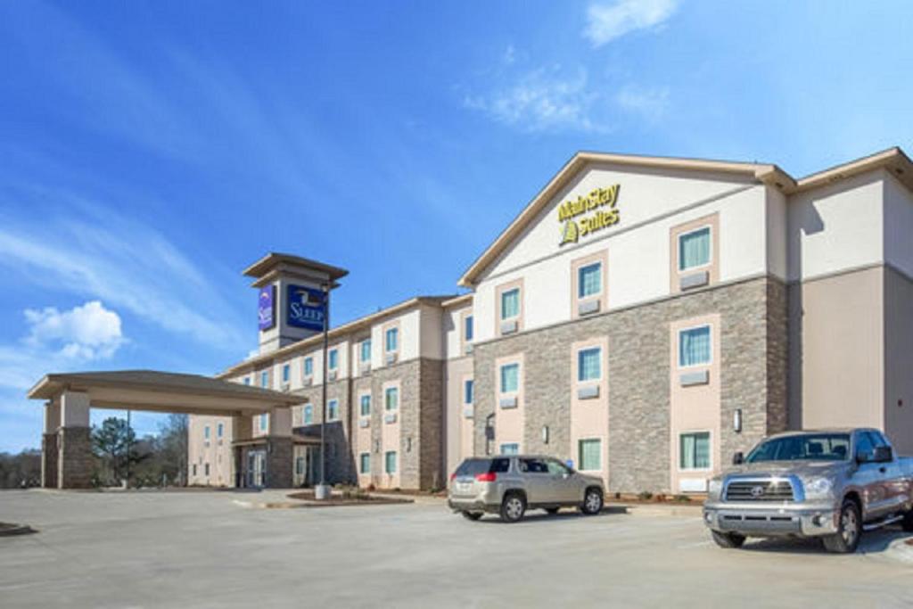 a hotel with two cars parked in a parking lot at MainStay Suites Meridian in Meridian