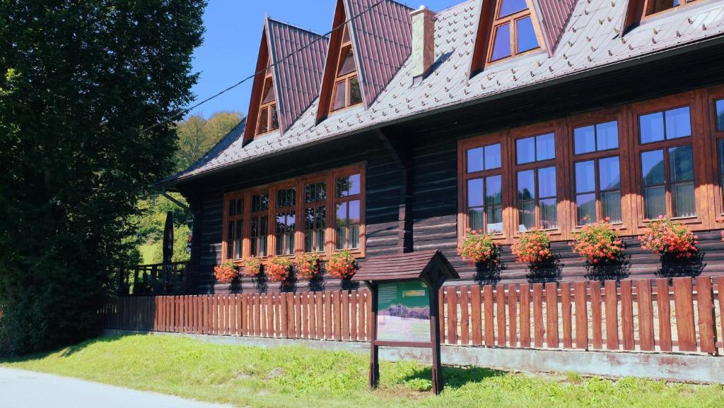Penzión Manín في بوفاجسكا بيستريتسا: منزل خشبي به خزاف من النباتات وسياج