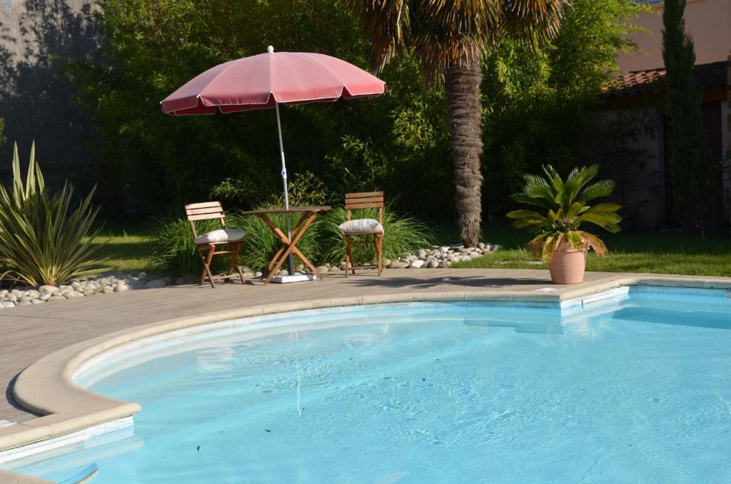 - une piscine avec une table et un parasol dans l'établissement Chambre D'hôtes Et Spa, à Agen