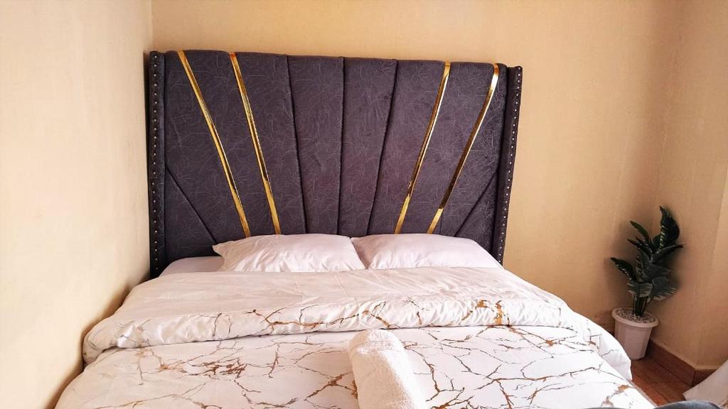 a bed with a black headboard in a bedroom at Deluxe Homes, Voi in Voi