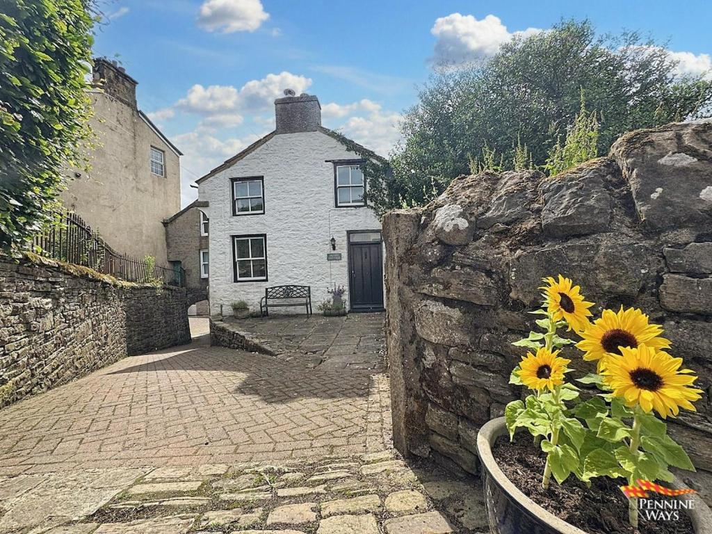 a house with a stone wall and a vase of flowers at Hundy Cottage in Alston